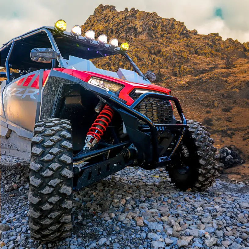 Off-road Polaris RZR vehicle with rugged tires on rocky terrain.